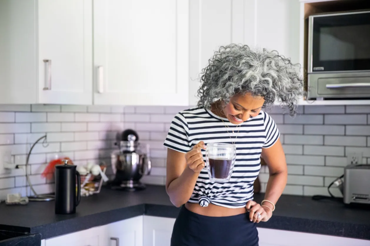 mature black woman drinking coffee as part of menopause morning routine.